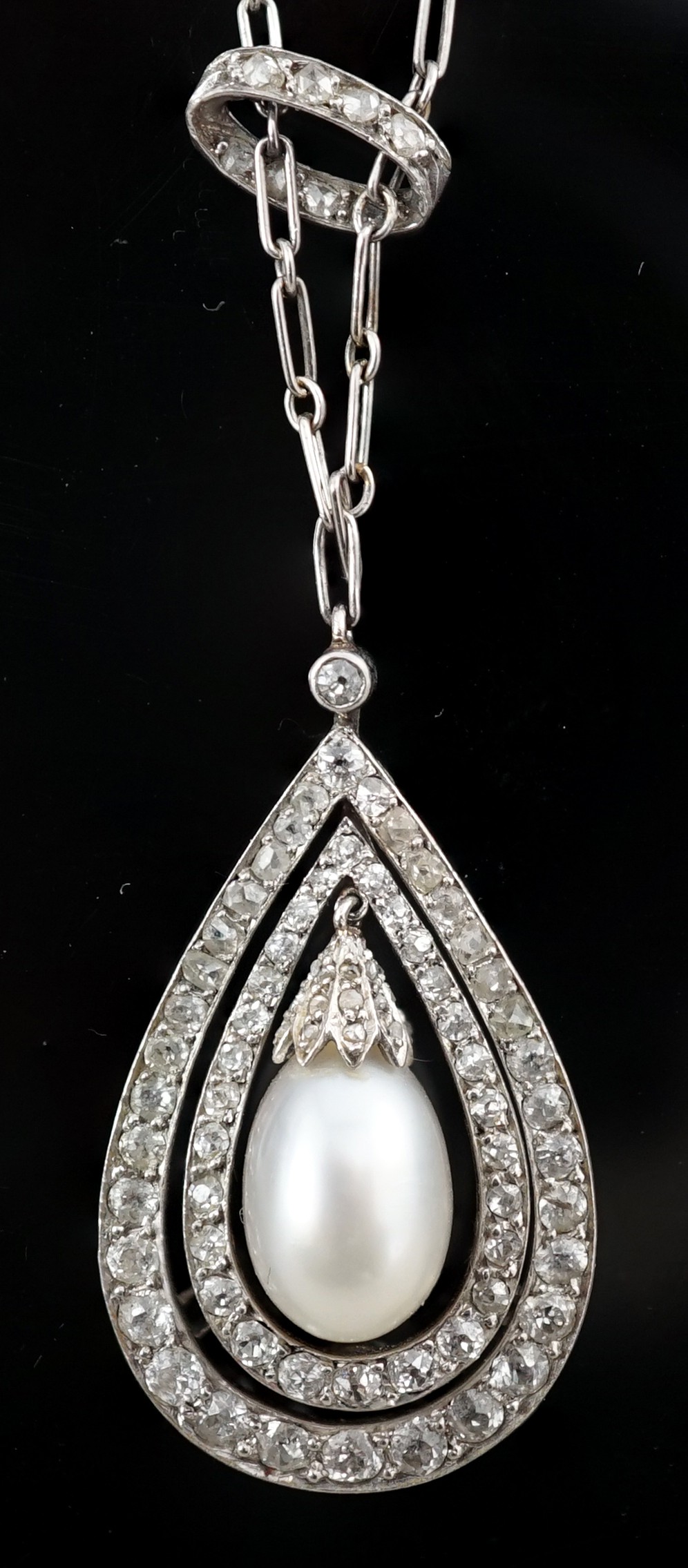 An early 20th century platinum, cultured? pearl and diamond cluster set pear shaped drop pendant necklace